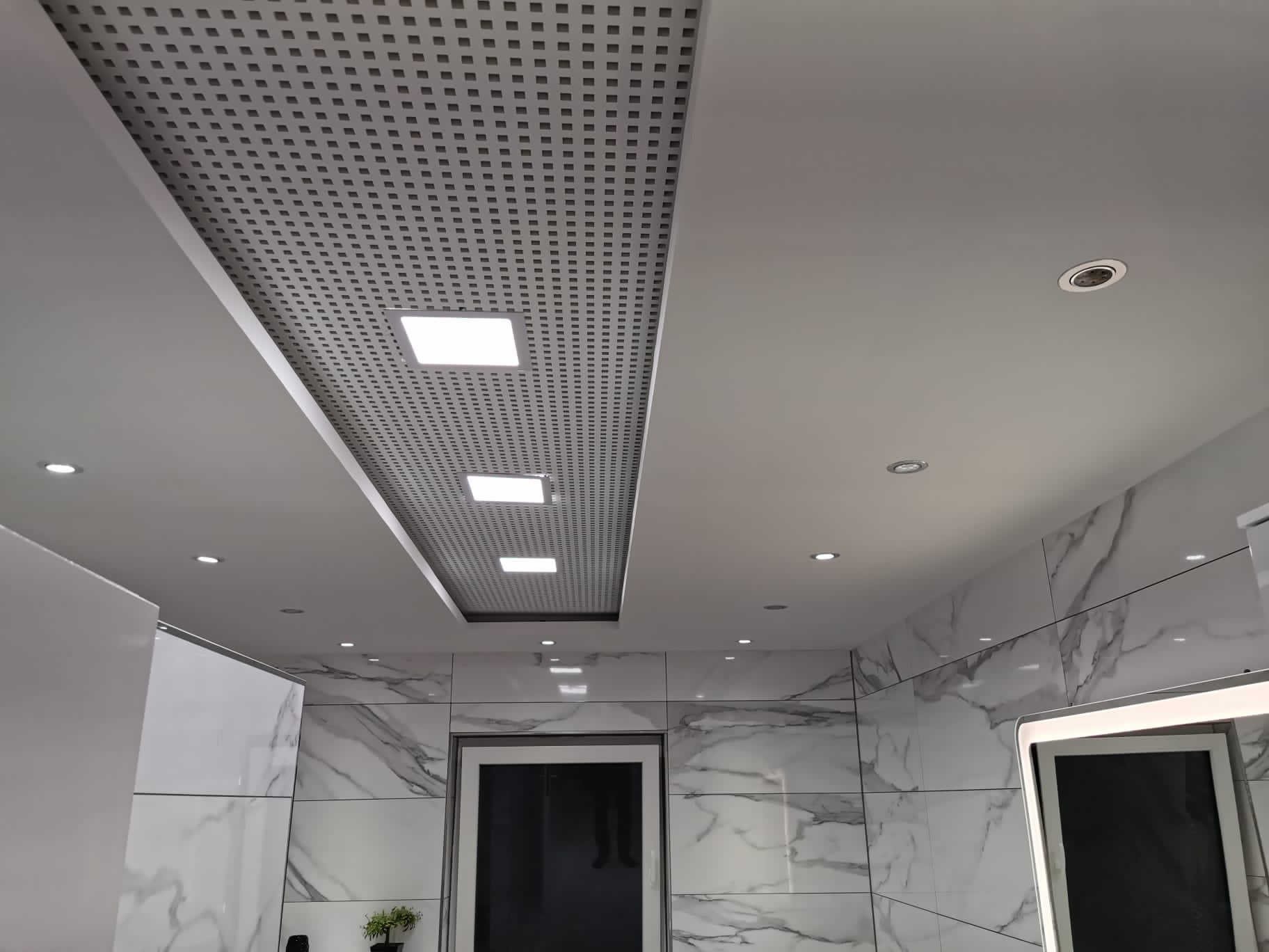 Moderne perforierte Akustikdecke mit integrierter Beleuchtung in einem fertig ausgebauten Innenraum